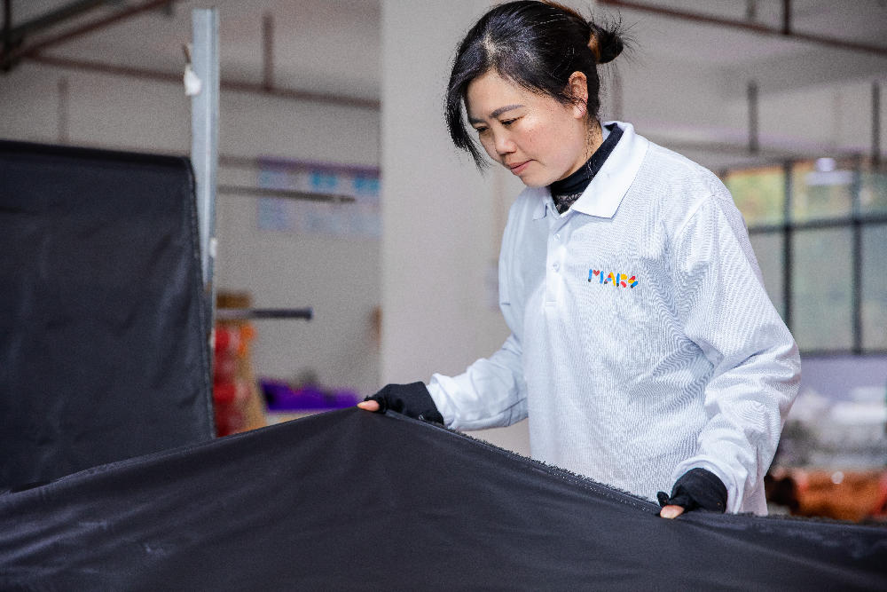 A staff member carefully inspects the incoming fabrics.