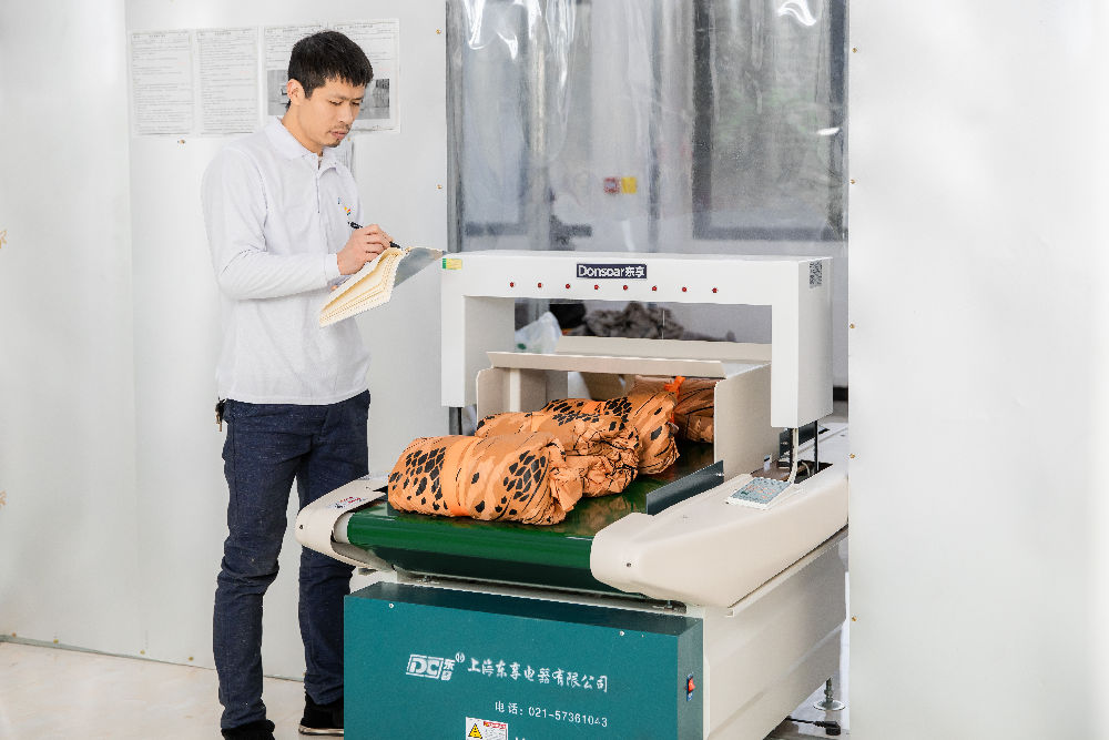 A worker is recording the product going through the needle inspection machine.