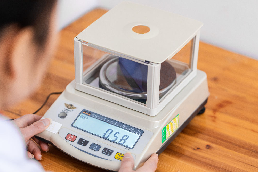 A worker performs a grammage test on raw materials.