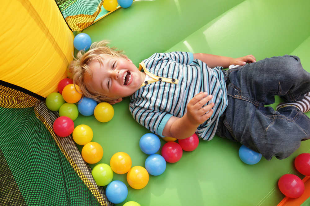 A young boy playing happily on an inflatable bounce house.