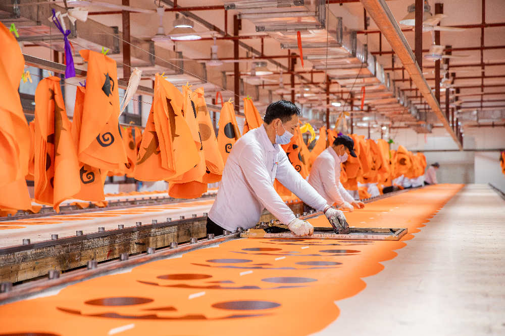 Two workers meticulously print products on the assembly line.